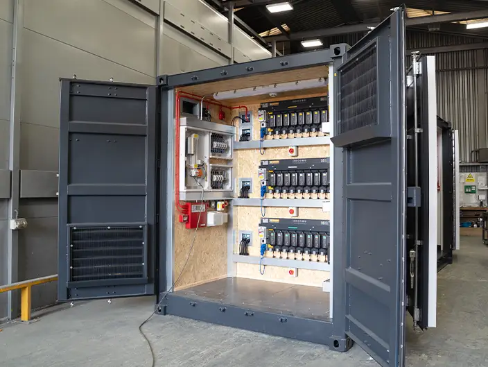 20ft high cube shipping container converted into a control panel room, featuring mounted electrical panels, wiring, and distribution boards inside an open container.