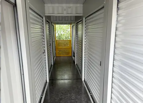 Interior walkway of a topper storage container with roller shutter doors, with a removable balustrade at end of the row.