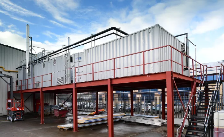 Containerised boiler room installed on a steel platform with stair access, integrated into a site setup.