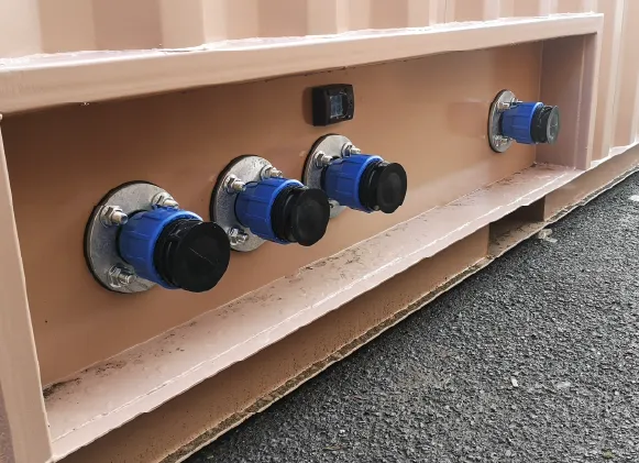 Close-up view of five industrial-grade blue and black electrical sockets mounted into a recessed panel on the side of a beige container.